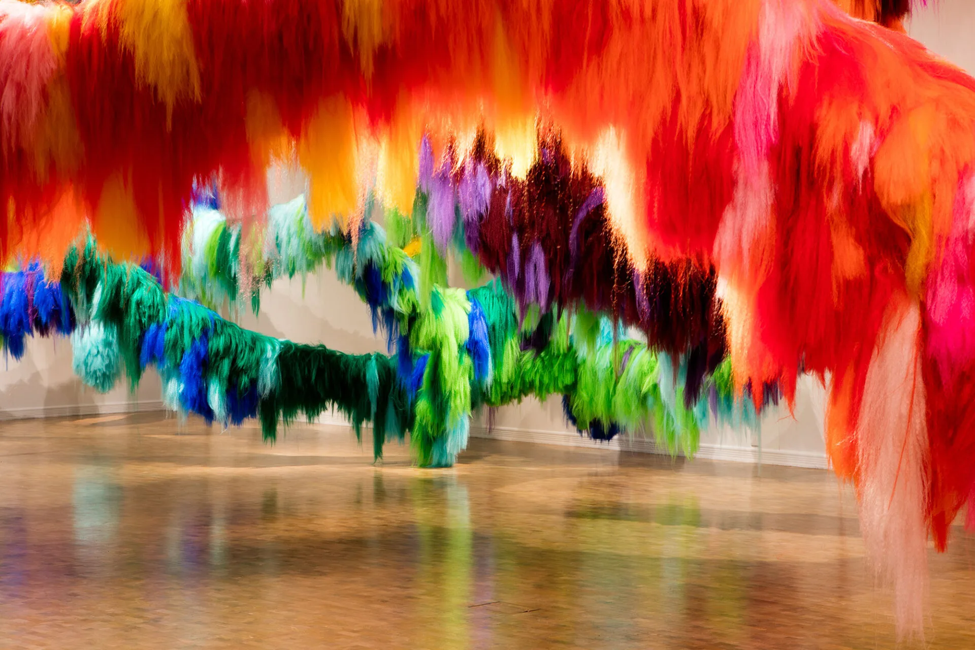 Colorful, fuzzy textile art installations hang from the ceiling at the Hilliard Art Museum, with cascading strands above a polished gallery floor—creating a vibrant, family friendly experience among top Louisiana museums.