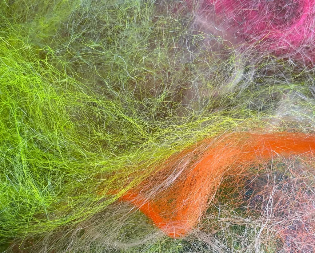 Close-up of tangled synthetic fibers in bright colors, creating a chaotic, textured pattern reminiscent of local art Lafayette—an abstract display that echoes the creativity found in Louisiana museums.