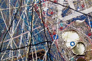 Abstract painting with intersecting lines, splatters, and shapes in various colors, including blue, red, white, and gold; metallic and shiny textures are visible throughout the composition.