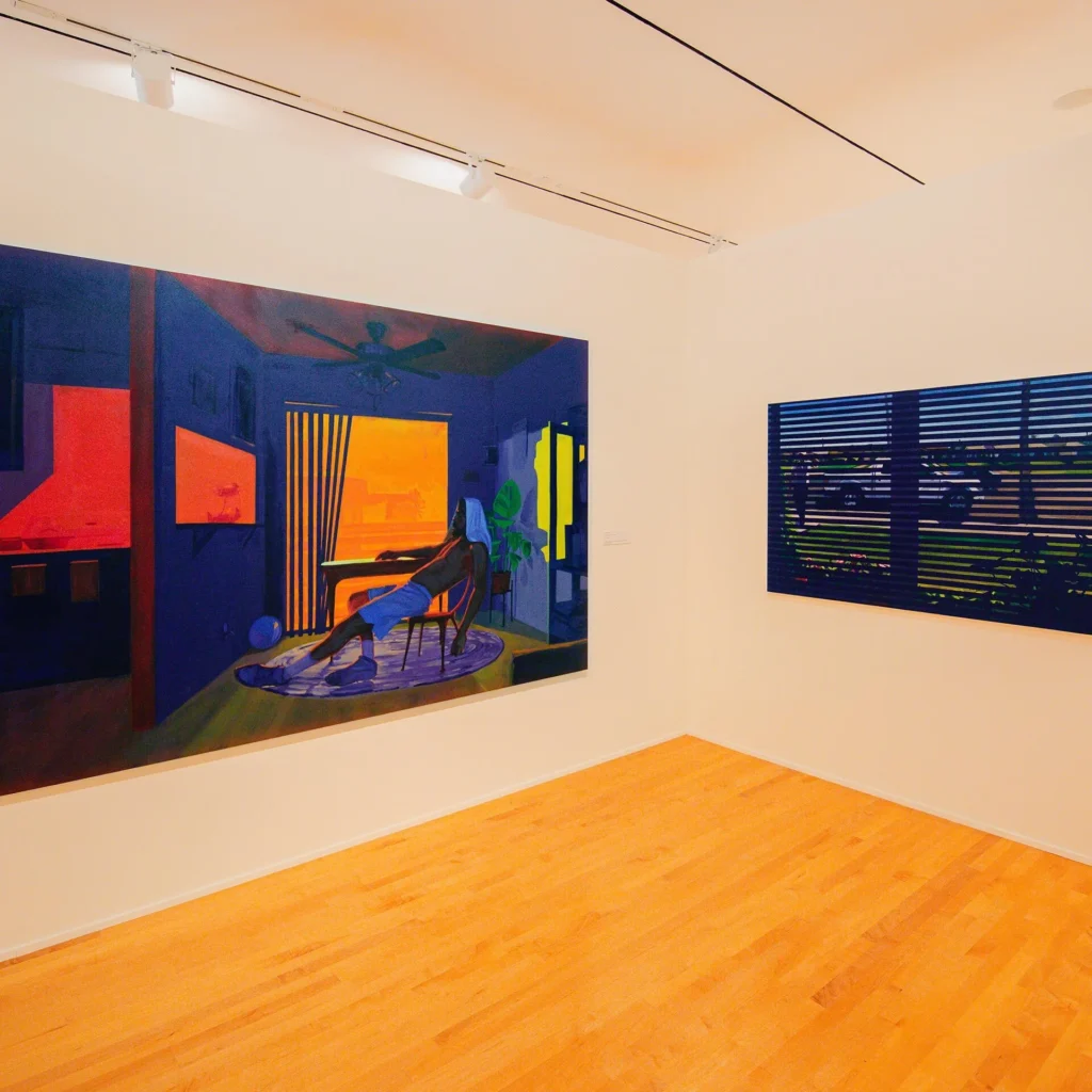 A brightly lit gallery room with two large paintings on white walls; the left painting shows a moody interior with warm orange and blue tones, while the right painting depicts a window with blinds and a dark outdoor scene.