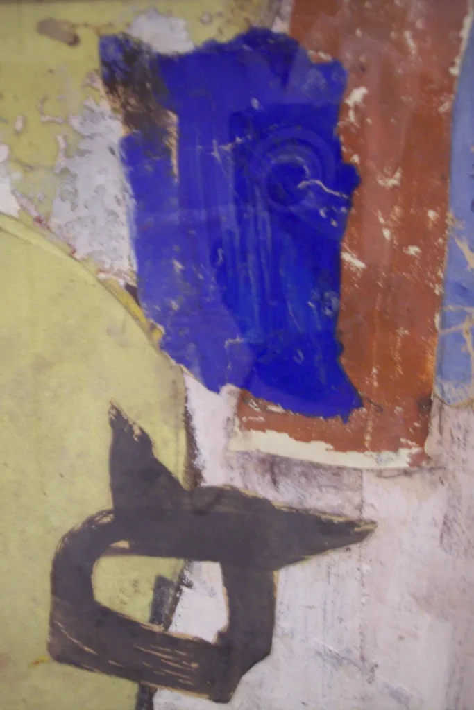 Abstract painting with patches of blue, brown, yellow-green, and white, featuring a bold black shape resembling an arrow or a stylized letter on a textured, weathered surface.