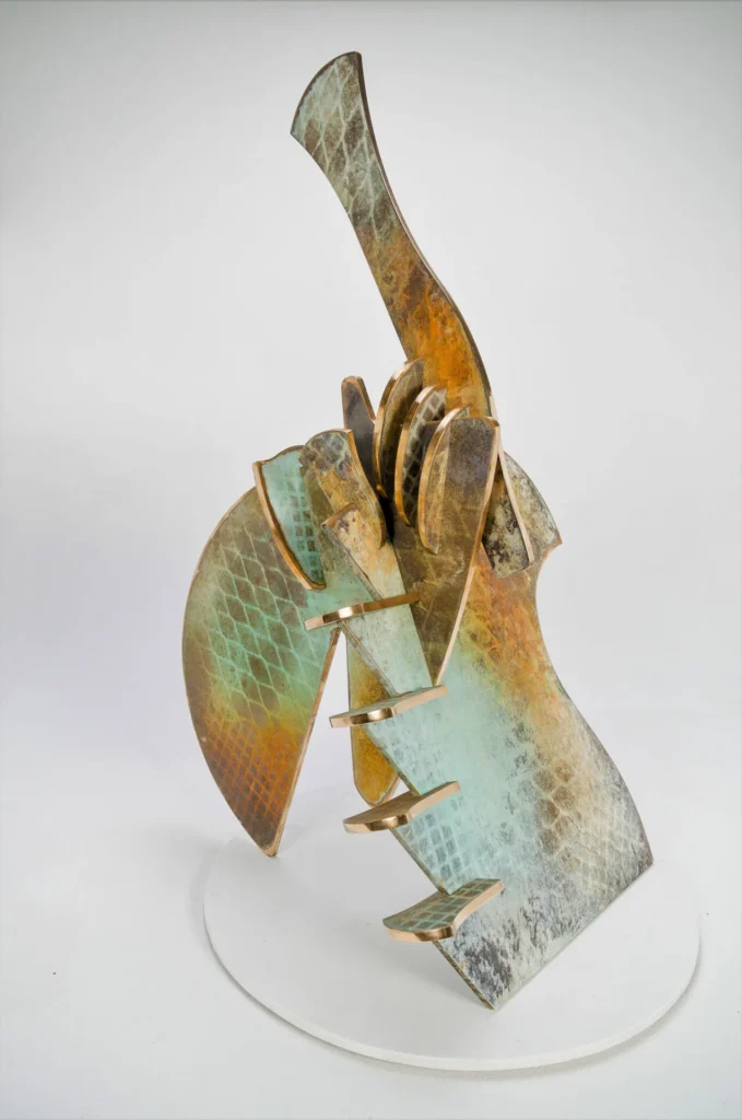 Abstract metal sculpture with geometric and curved shapes, textured with green, blue, brown, and bronze tones in a manner reminiscent of Elemore Morgan Jr., standing on a round white base against a plain background.